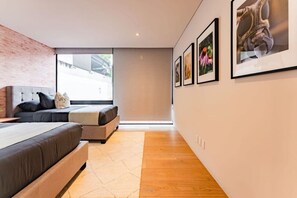 A modern bedroom with a large bed, a sofa, and a window with a view. - Polanco Penthouse: Rooftop Swing & City Views (Mexico City)