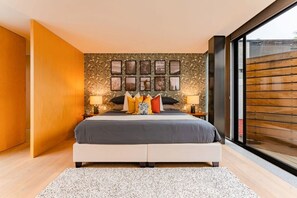 Une chambre moderne avec un grand lit, un mur décoratif et une vue par la fenêtre.