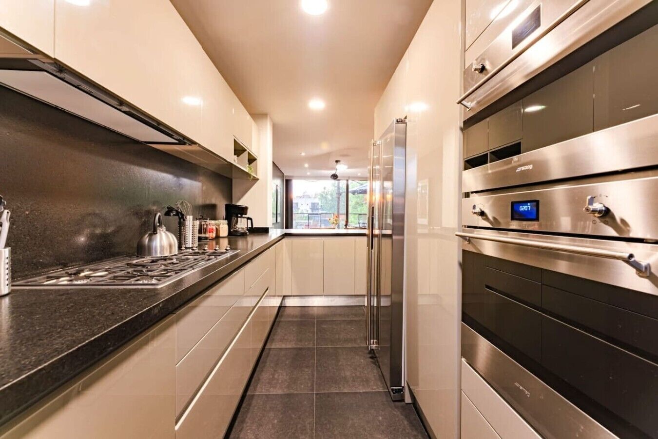 A modern kitchen with stainless steel appliances, a central island, and a view to the outdoors.