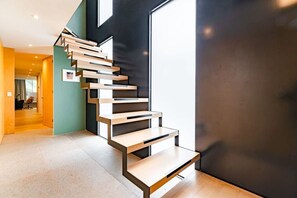 Eine moderne Treppe mit minimalistischem Design, die zu einem Raum mit großem Fenster führt.