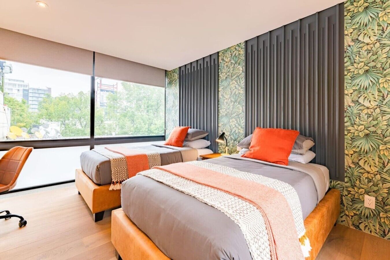 Une chambre moderne avec deux lits, une grande fenêtre et une vue sur la ville.