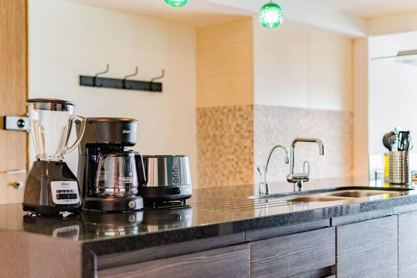 A modern kitchen with a coffee maker, a blender, and a kettle on the counter.