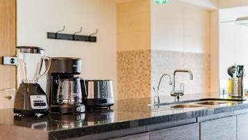 A modern kitchen with a coffee maker, a blender, and a kettle on the counter.
