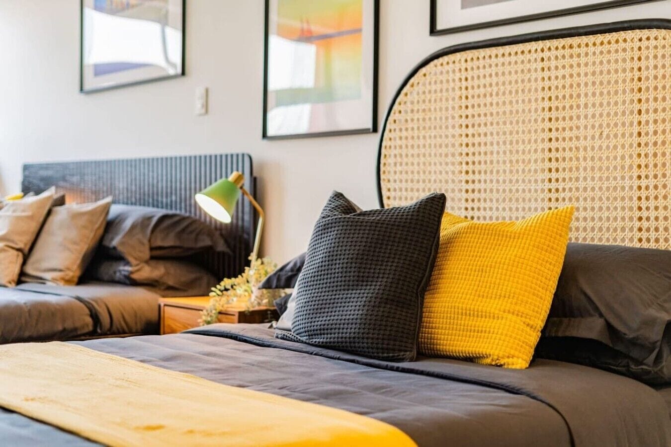 Een moderne slaapkamer met een bed, nachtkastje, lamp en hoofdeinde.