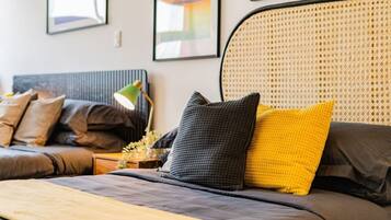 Een moderne slaapkamer met een bed, nachtkastje, lamp en hoofdeinde.