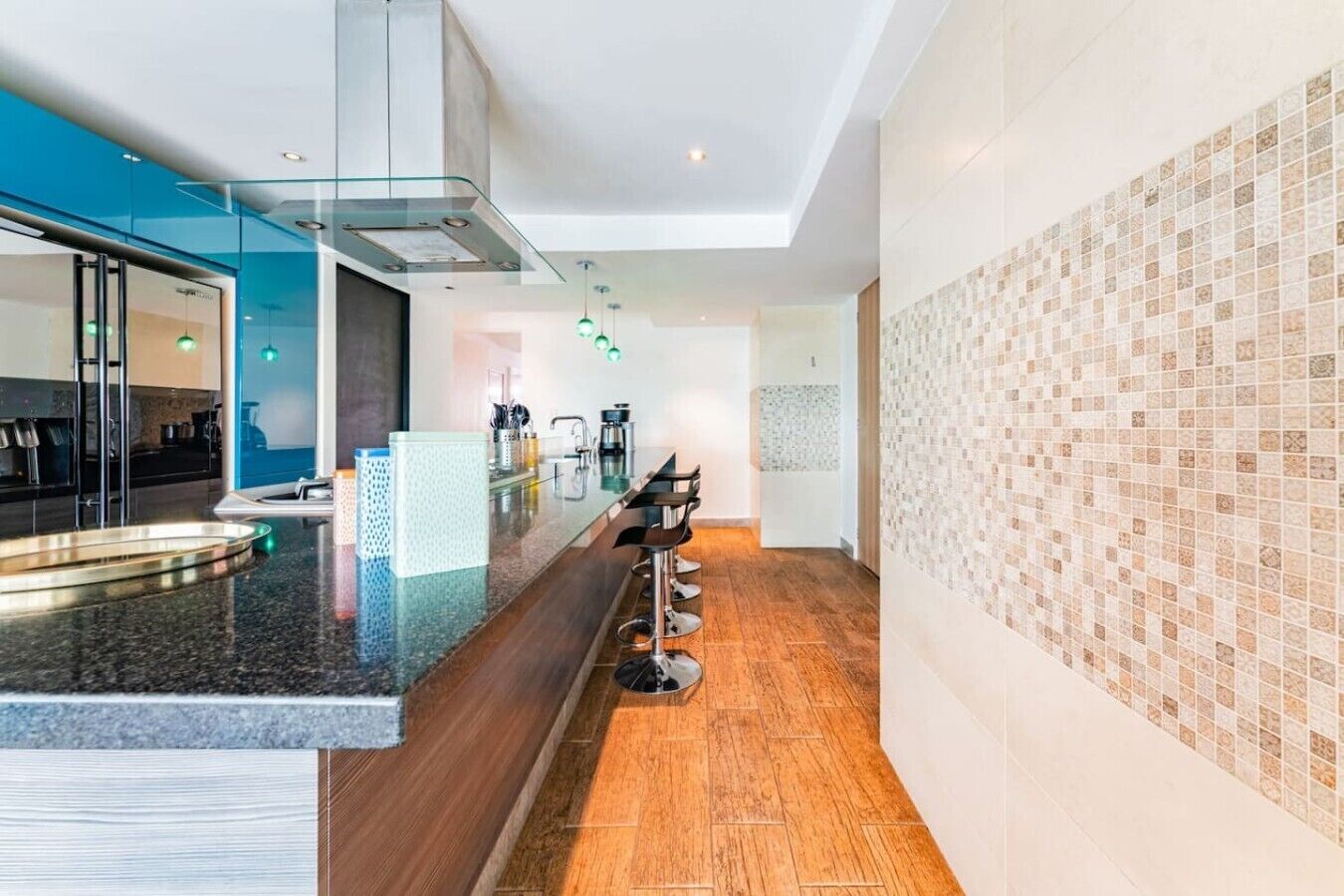 Een moderne keuken met een glazen scheiding, een bar met krukken, en een behangwand.