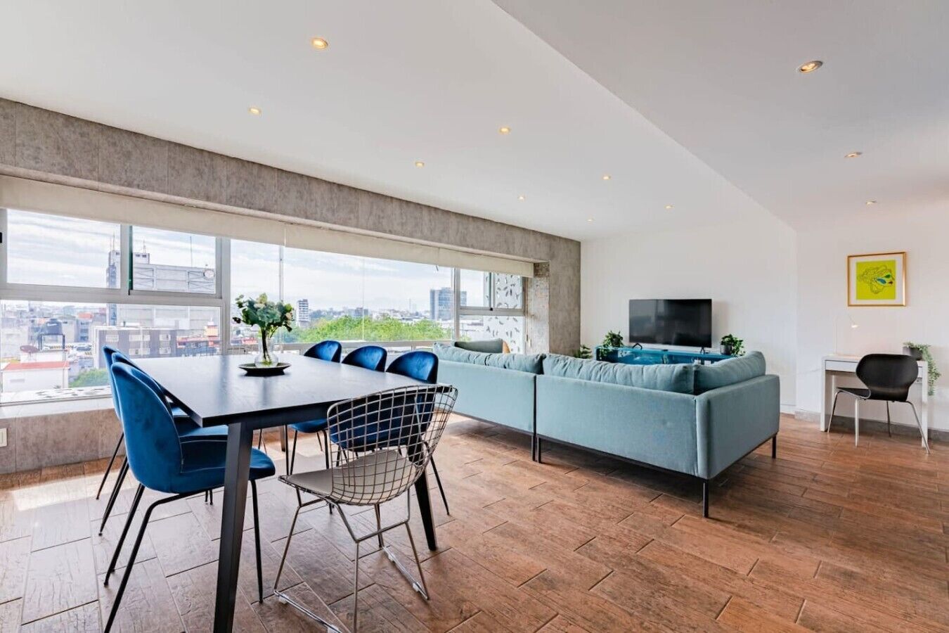A modern living space with a dining area, a sofa, and a TV.