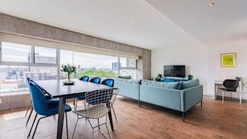 A modern living space with a dining area, a sofa, and a TV.