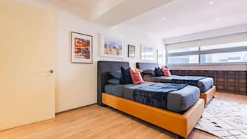 A modern bedroom with two beds, a large window, and artwork on the walls.