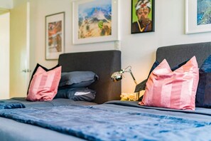 A bedroom with two beds, each with a dark headboard and multiple pillows. - Pet Friendly Condo | Walkable, Food & Nightlife (Juárez)