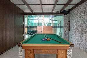 Una mesa de billar con bolas, estructura de madera y una red.