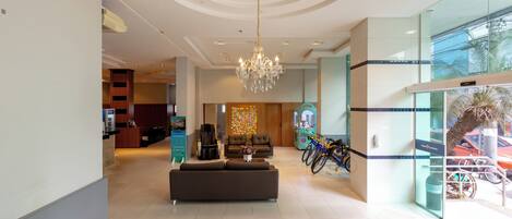A hotel lobby with a reception desk, seating area, and a chandelier.