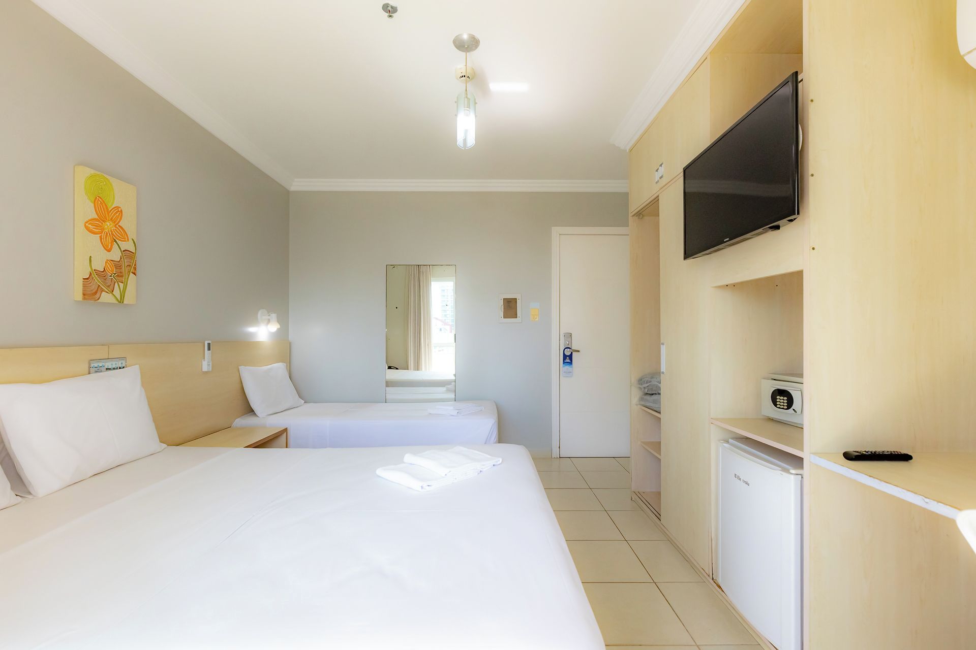Une chambre d’hôtel avec deux lits, une télévision, un four à micro-ondes et un petit réfrigérateur.