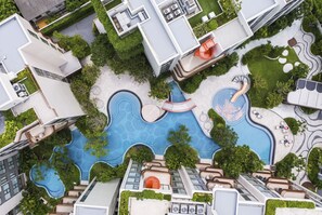 Un edificio moderno con piscina en la azotea, zona de estar al aire libre y abundante vegetación.
