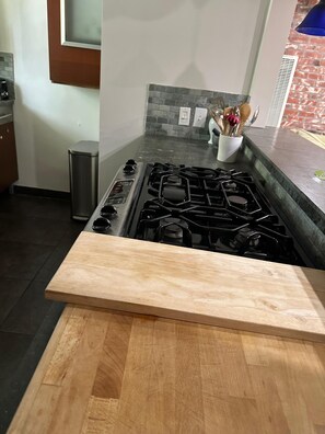A kitchen with a gas stove, a trash can, and a wooden countertop. - Santa Monica two bedroom apartment SM5 (Santa Monica)