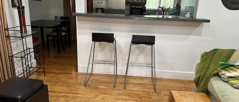 Una cocina moderna con una isla central, taburetes de bar y un comedor con mesa y sillas.