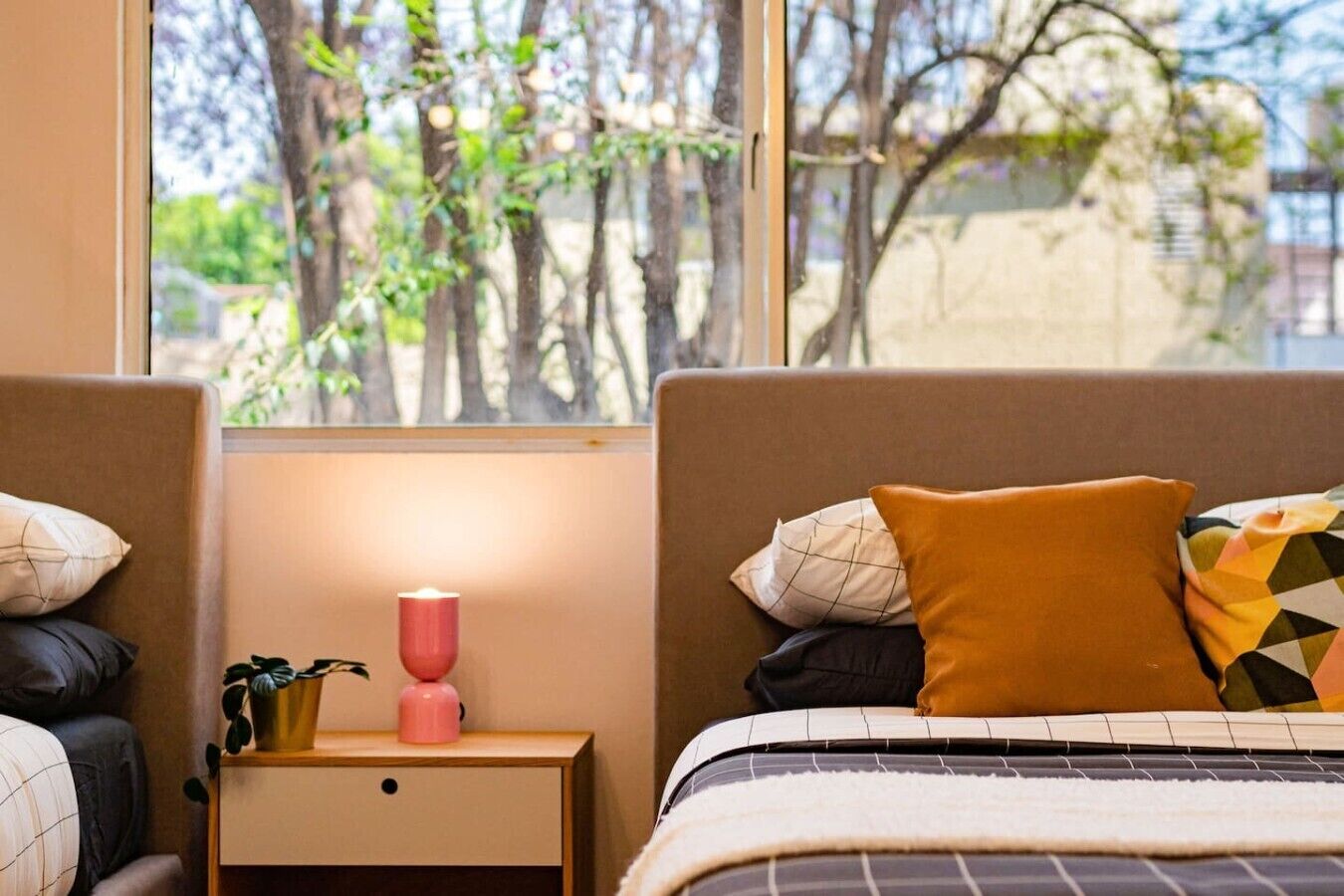 A bedroom with a bed, a nightstand, a lamp, and a window with a view of trees.