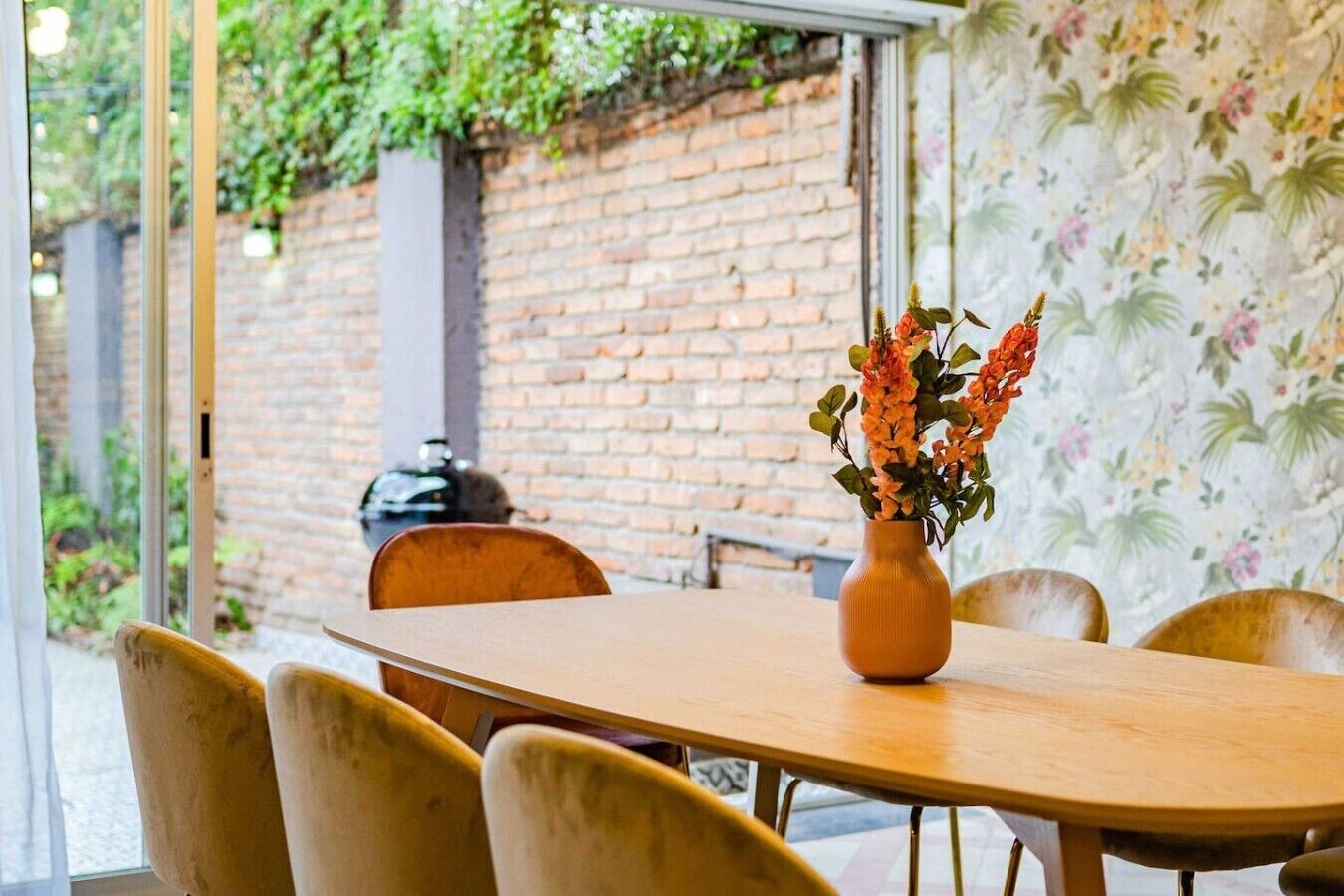 Un comedor con pared de ladrillo, mesa de madera y sillas.