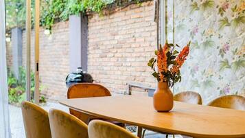 Un comedor con pared de ladrillo, mesa de madera y sillas.
