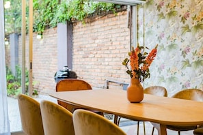 Un comedor con pared de ladrillo, mesa de madera y sillas.