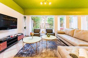 A living room with a sofa, two armchairs, a coffee table, and a TV.