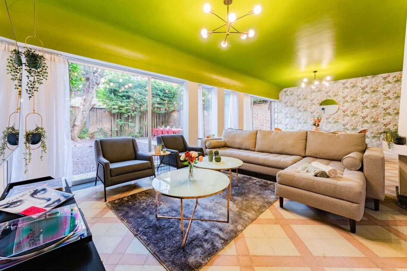 A living room with a sofa, chairs, a coffee table, and hanging plants.