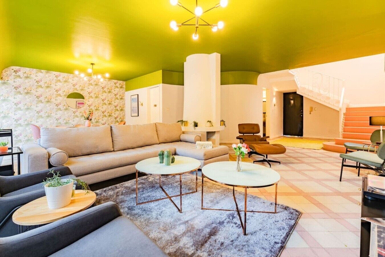 A modern living room with a sofa, two coffee tables, and a patterned wall.