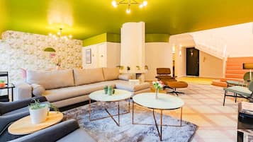 A modern living room with a sofa, two coffee tables, and a patterned wall.