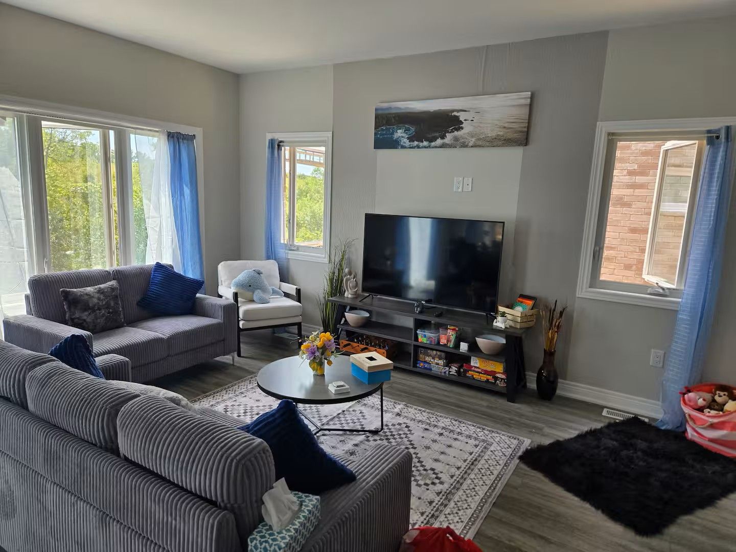 Ein Wohnzimmer mit einer Couch, einem Sessel, einem Couchtisch, einem Fernseher und einem Bücherregal.