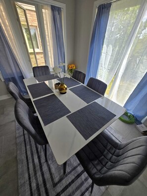 A dining area with a long table, dark chairs, and a vase with flowers.