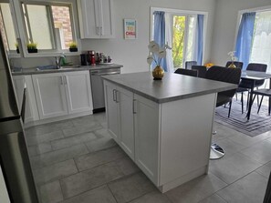 Une cuisine moderne avec des meubles blancs, un îlot central et un coin repas comprenant une table et des chaises.