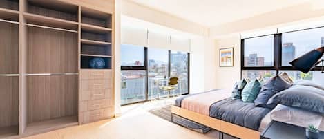 Une chambre moderne avec un grand lit, un placard intégré et une vue sur la ville.