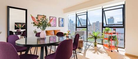 Un salon moderne avec un coin repas, de grandes fenêtres et une vue sur la ville.