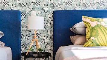 A bedroom with a zebra-patterned wallpaper, a bedside table with a lamp, and a bed with pillows.