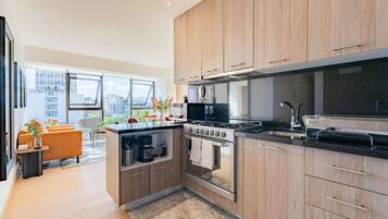 A modern kitchen with wooden cabinets, a built-in oven, and a large window overlooking a cityscape.