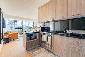 A modern kitchen with wooden cabinets, a built-in oven, and a large window overlooking a cityscape. - City Views & Private Terrace in Trendy Roma (Mexico City)