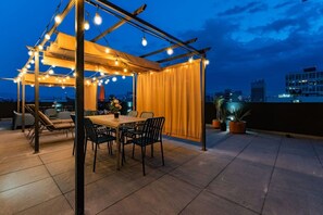 An outdoor patio with a table and chairs, string lights, and potted plants. - City Views & Private Terrace in Trendy Roma (Mexico City)