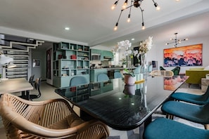 A modern kitchen with a dining area, featuring a glass-top table, wicker chairs, and teal cabinetry. - Private Terrace Escape in the Heart of Roma Norte (Mexico City)