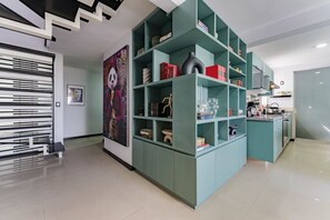 A modern interior with teal shelving units, a kitchen area, and a staircase with a black and white design. - Private Terrace Escape in the Heart of Roma Norte (Mexico City)