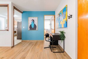 A hallway with a blue wall, a wooden floor, a desk with a chair, and a plant. - Roma Norte Stay • Pet Friendly, Walk to Cafés (Mexico City)