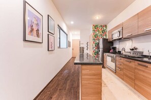 A modern kitchen with wooden cabinets, a central island, and a microwave. - Best for Groups in Roma Norte: Parking, Workspaces (Mexico City)