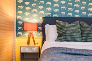 A hotel room with a bed, pillows, a nightstand, a lamp, and a wall with animal prints. - Best for Groups in Roma Norte: Parking, Workspaces (Mexico City)