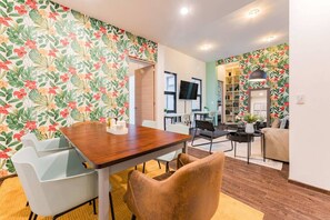 A modern living room with a dining area, featuring a wooden table, chairs, a sofa, and a bookshelf. - Best for Groups in Roma Norte: Parking, Workspaces (Mexico City)