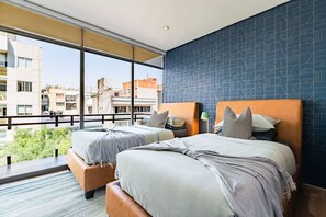 Ein Hotelzimmer mit zwei Betten, einem großen Fenster und Blick auf die Stadt.