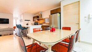 A modern kitchen with a dining area, a TV, and a sofa. - 2 Condos in La Roma | Parking, Perfect for Groups (Mexico City)