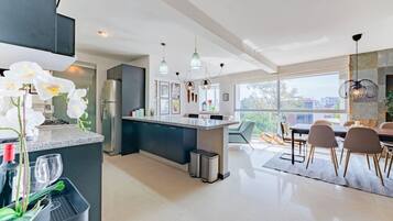 A modern kitchen with a central island, dining area with chairs, and large windows.
