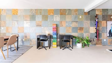A modern office space with two desks, chairs, a potted plant, and a colorful vertical art installation.