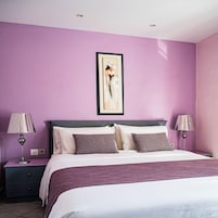 Un dormitorio con una cama, dos mesitas de noche y una obra de arte colgada en la pared.