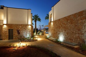 Un patio con paredes de piedra, palmeras y un molino en el fondo.