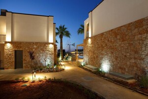 Un patio con paredes de piedra, palmeras y un molino en el fondo.